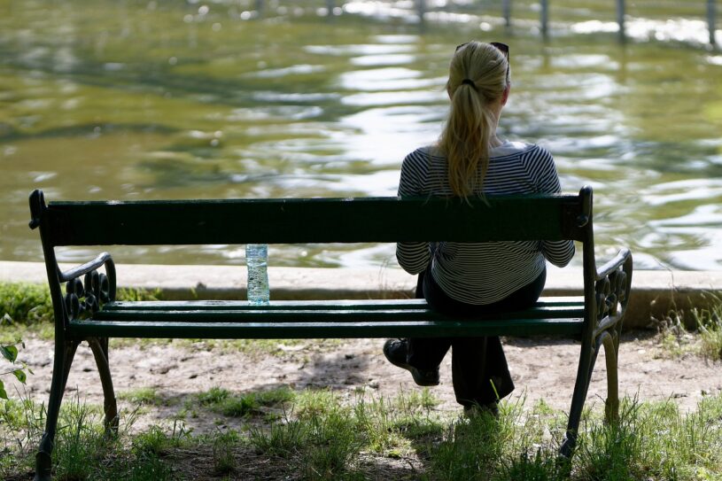 vrouw ontspant op bankje in het park aan het water